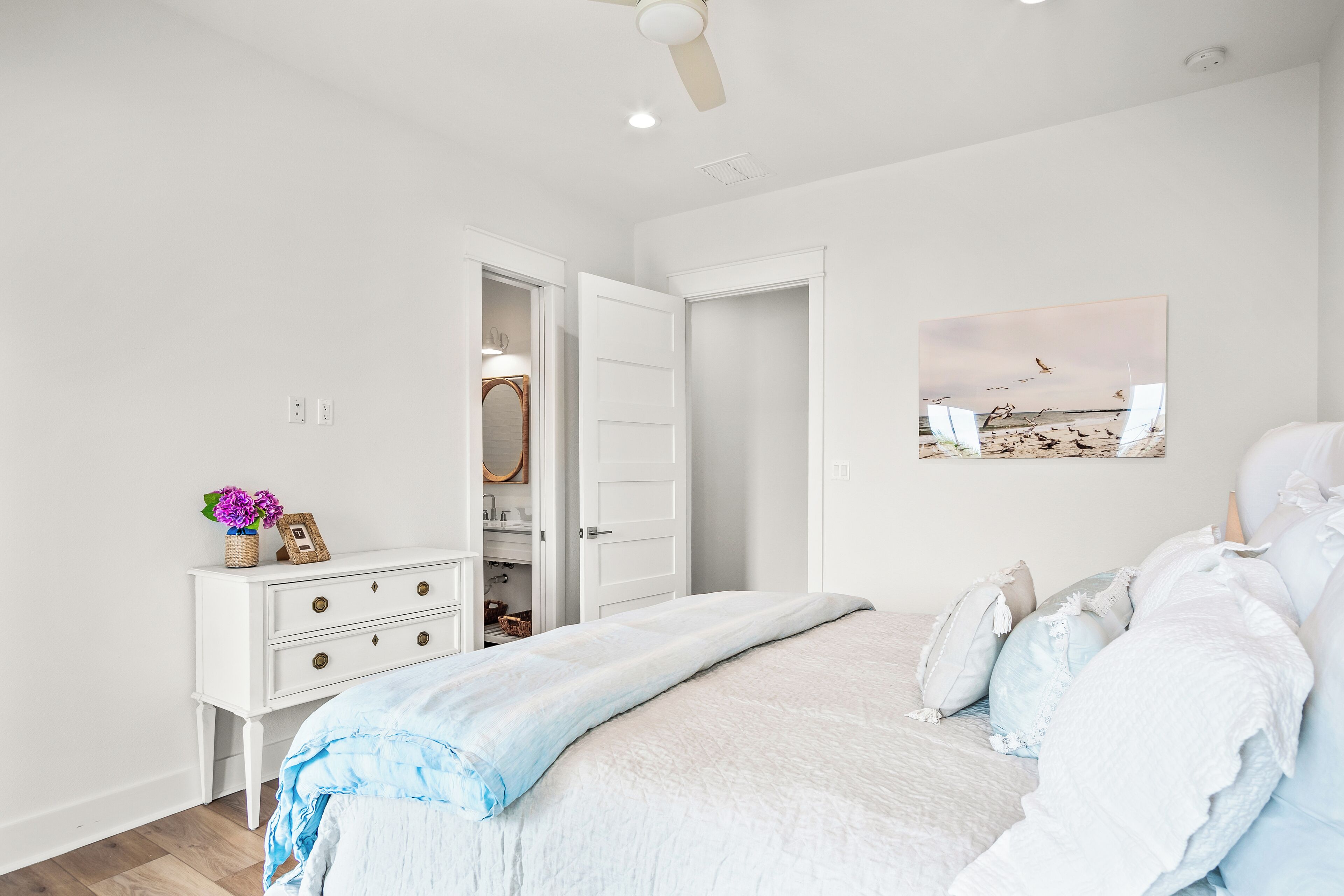 Een slaapkamer met een bed, een dressoir en een plafondventilator.