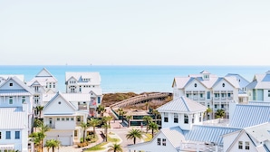 A coastal residential area with white buildings, a wooden pier, and a view of the ocean.