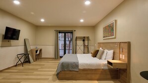A bedroom with a bed, bedside table, TV, and a window with curtains. - Suites el Consuelo (Oaxaca)