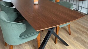 A modern dining area with a wooden table, green upholstered chairs, and a lit candle. - Charming 3-bedroom house in Louisa within 2 miles of town. (Louisa)