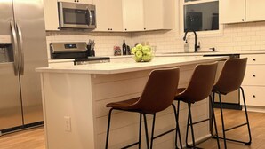 A kitchen with a central island, bar stools, stainless steel appliances, and white cabinetry. - Charming 3-bedroom house in Louisa within 2 miles of town. (Louisa)