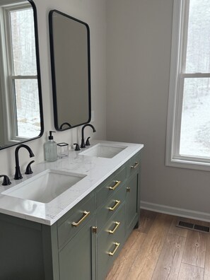 Bathroom features a dual sink vanity with a marble countertop and gold handles.