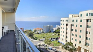 Balkon med havudsigt, parkeringsområde og omkringliggende bygninger.