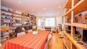 A cozy living room with a striped table, wooden bookshelves, a sofa, and a TV.