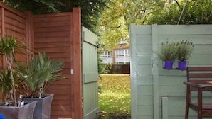 A wooden deck with potted plants, a bench, and a green fence.
