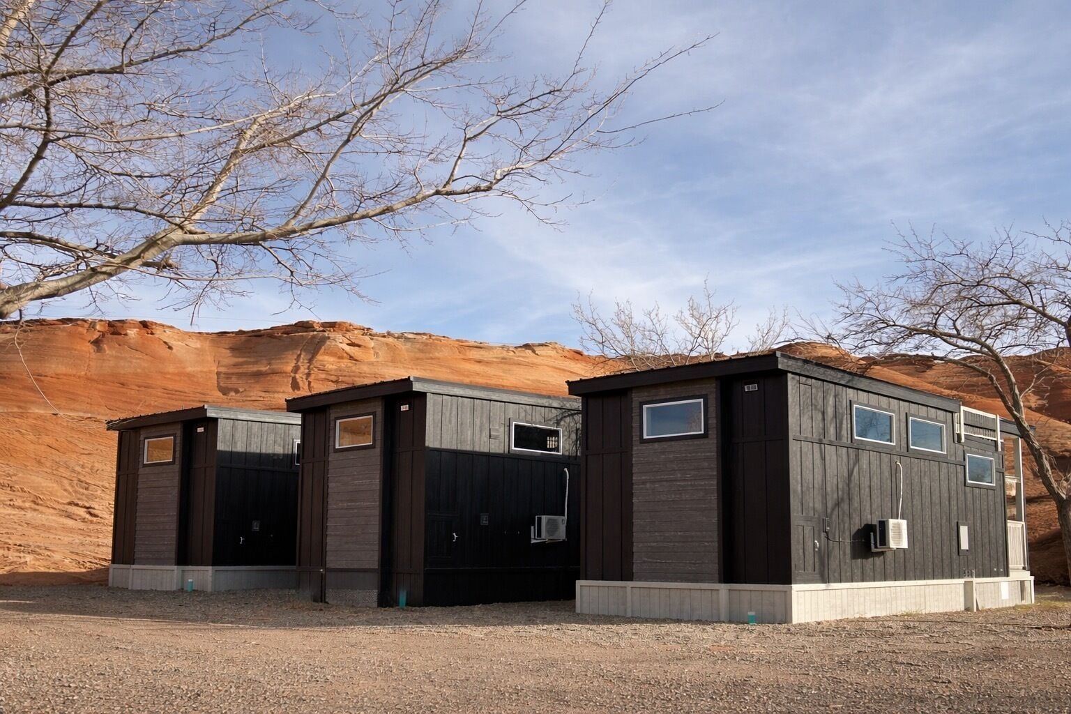 Un bâtiment moderne doté de deux entrées, de grandes fenêtres et d’un sol recouvert de gravier.