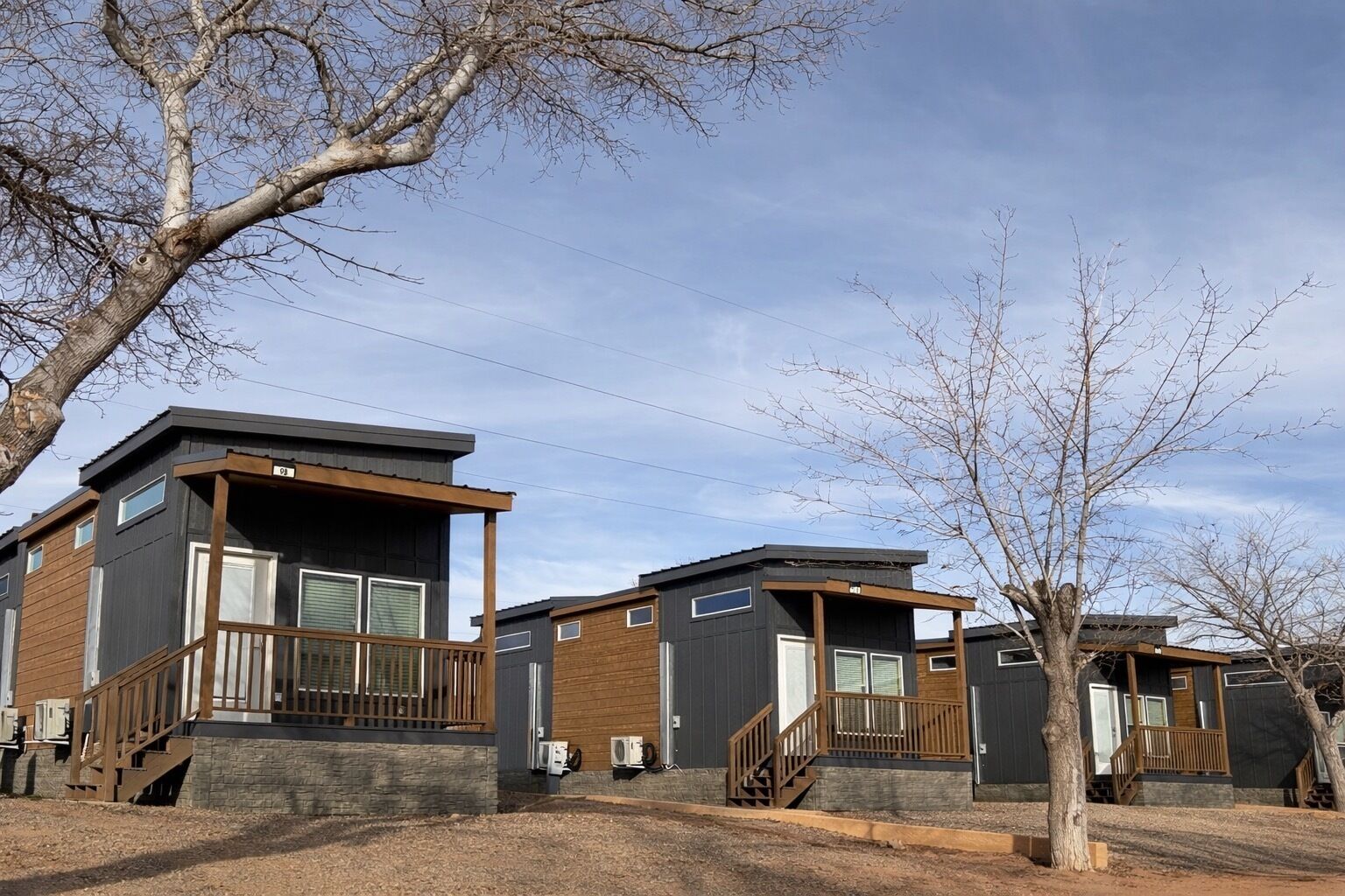 A row of modern, two-story cabins with wooden balconies and large windows.