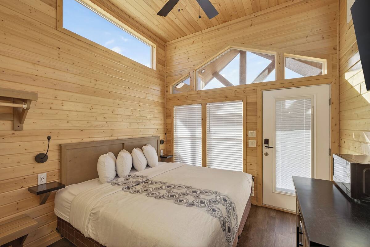 Une chambre dans un chalet en bois, avec un lit, un bureau et une grande fenêtre.