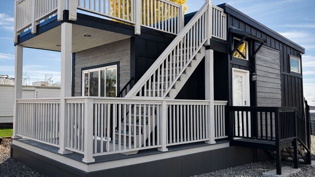 A two-story house with a balcony, a staircase, and a small deck area. - Luxury Tiny Homes - Deluxe King Room (Page)