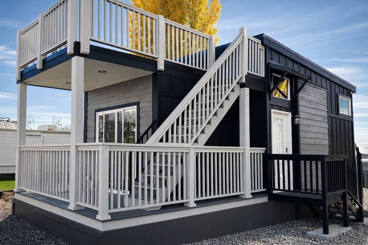 Une maison à deux étages avec un balcon, un escalier et une petite terrasse.