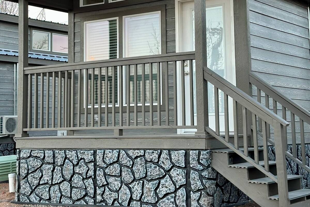 Une maison à deux étages, avec des fondations en pierre et une terrasse en bois.