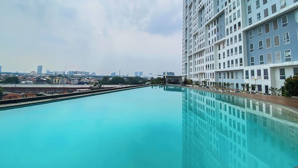 Una piscina en la azotea con vista panorámica de la ciudad, rodeada de edificios altos.