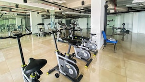 Un gimnasio con bicicletas estáticas, cinta de correr y máquina de remo.