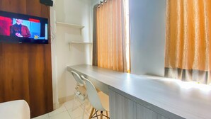 Una cocina moderna con encimera de madera, una silla blanca y un televisor montado en la pared.