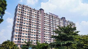 A high-rise hotel with multiple floors, a prominent sign at the top, and a clear view of the surrounding trees. - Homey 2Br Furnished Apartment At The Edge Bandung (Cimahi)