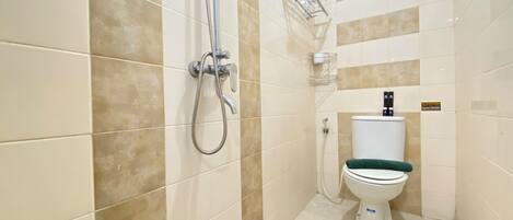 A bathroom with beige tiles, a shower, a toilet, and a towel rack.