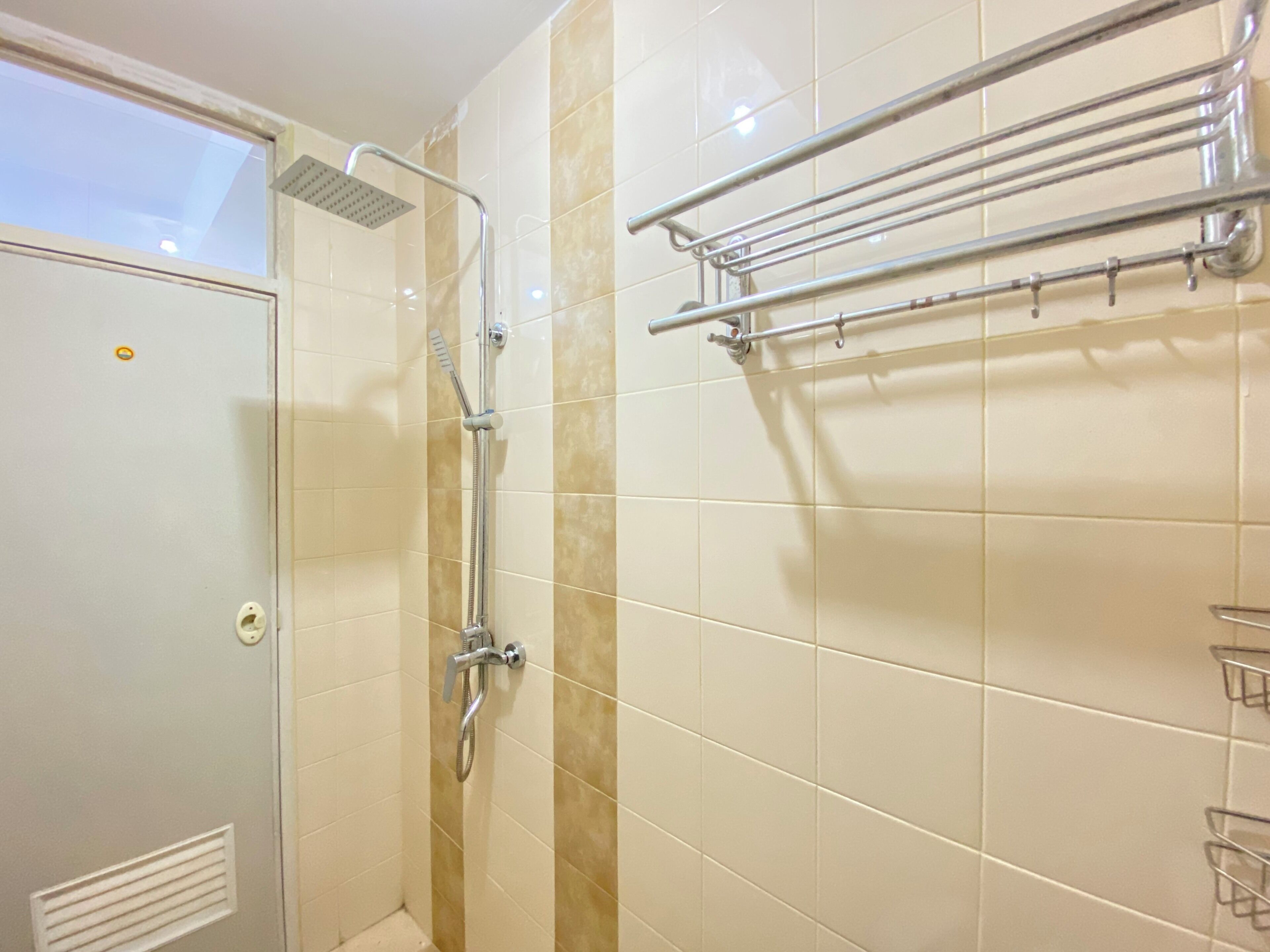 Et badeværelse med bruser, håndklædetørre og toilet.