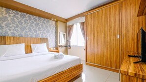 Un dormitorio con estructura de cama de madera, un armario grande, un televisor de pantalla plana y una ventana con cortinas.