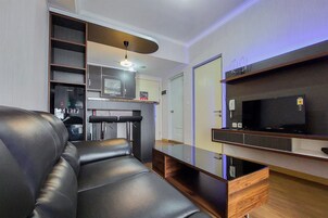 Una sala de estar moderna con un sofá de cuero, un televisor de pantalla plana y estanterías empotradas.