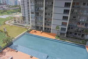 Un immeuble d’appartements moderne doté d’une piscine sur le toit, de balcons et offrant une vue sur les environs.
