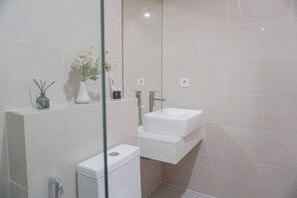 Une salle de bain moderne avec un lavabo blanc, des toilettes et une douche à parois de verre.