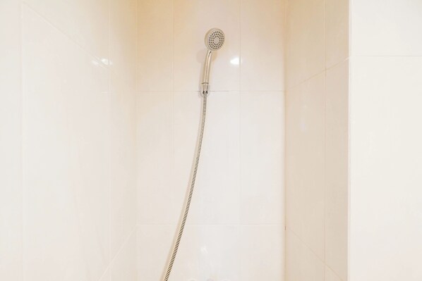 A shower with a handheld hose in a bathroom with white tiled walls. - Simply And Homey Studio At Evenciio Margonda Apartment (Depok)