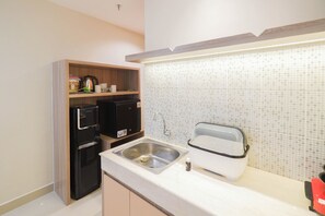 Compact kitchen with microwave, refrigerator, sink, faucet, and toaster.