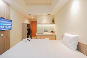 Cozy retreat with a flat-screen TV, kitchenette, and potted plant.