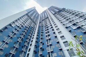 High-rise building with modern design, featuring grid-like facade and spacious balconies with railings and air conditioning units.
