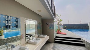 A modern bathroom with three sinks, large mirrors, and a view of a swimming pool.