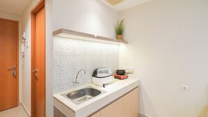 A compact kitchen with a sink, a toaster, and a small plant on the countertop.