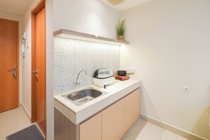 Compact kitchen with stainless steel sink, induction cooktop, and potted plant.