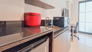 A modern kitchen with a red pot on the counter, a black appliance, and a window with blinds. - Cozy And Enjoy Living Studio (No Kitchen) Apartment At Skales Residence Nusa Dua Bali (Nusa Dua)
