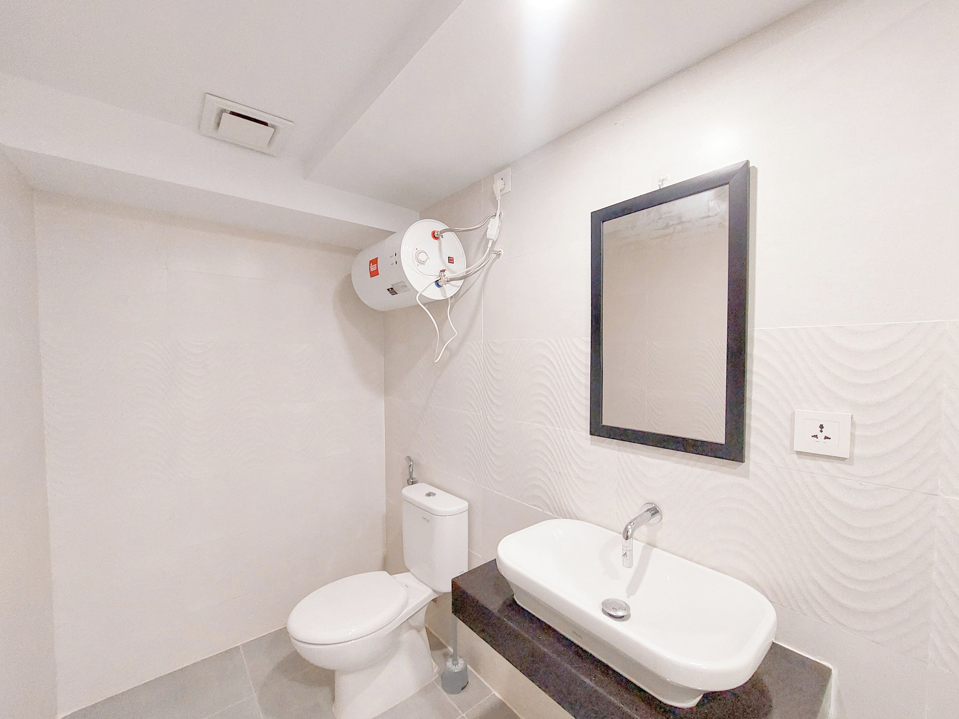 Un baño con inodoro, lavamanos y espejo.