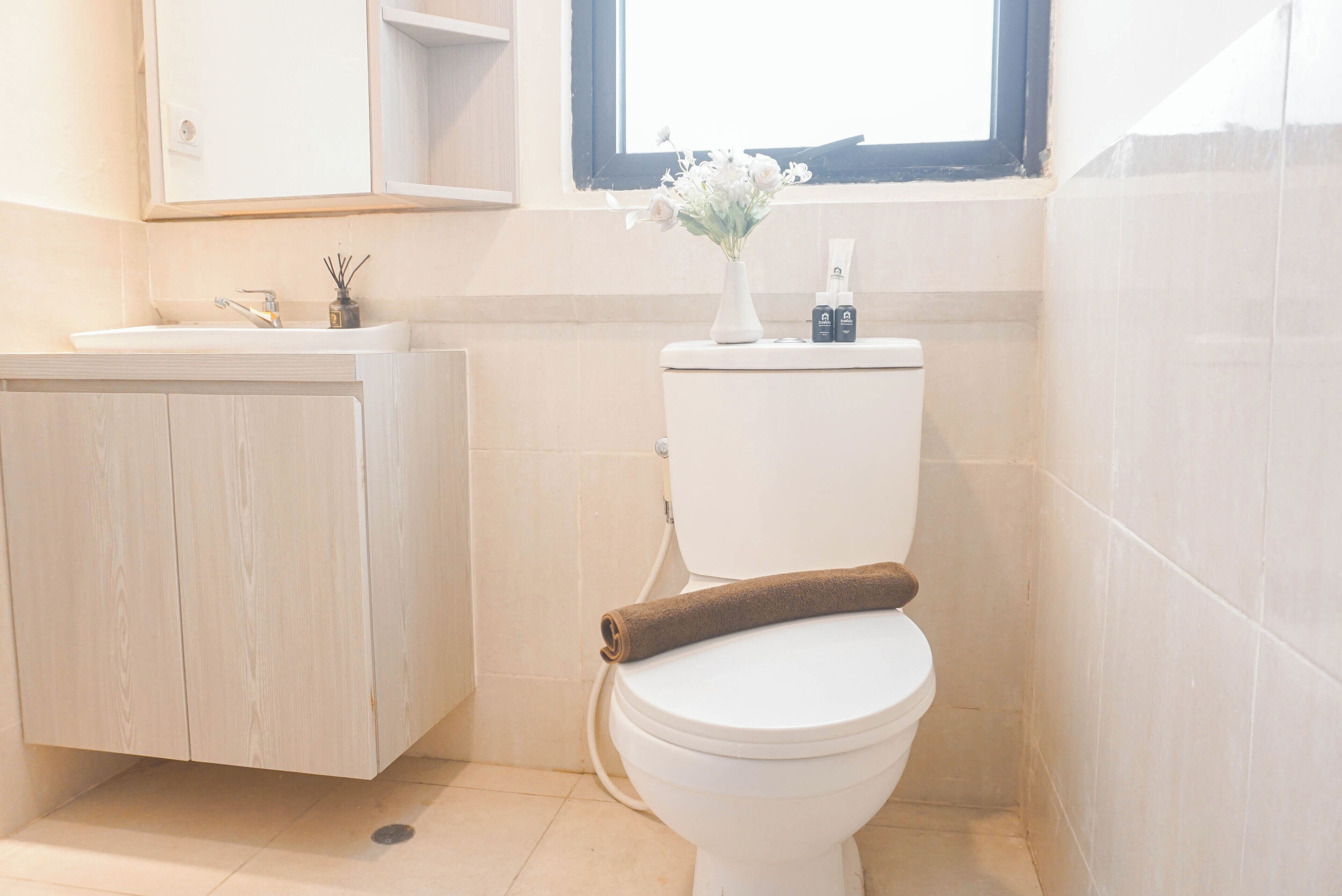 A bathroom with a toilet, a sink, a mirror, and a window.