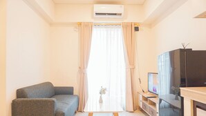 Ein Wohnzimmer mit grauem Sofa, einem weißen Couchtisch, einem Fernseher und einem schwarzen Schrank.