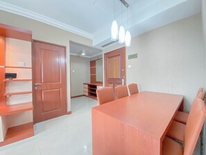 A spacious dining area with a large wooden table and matching chairs, flanked by wooden cabinets and a mirror. - The Signature Suite 3Br At Galeri Ciumbuleuit 1 Apartment (Bandung)