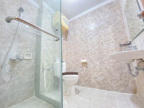 A modern bathroom with a glass shower enclosure, a white toilet, and a sink with a mirror. - The Signature Suite 3Br At Galeri Ciumbuleuit 1 Apartment (Bandung)