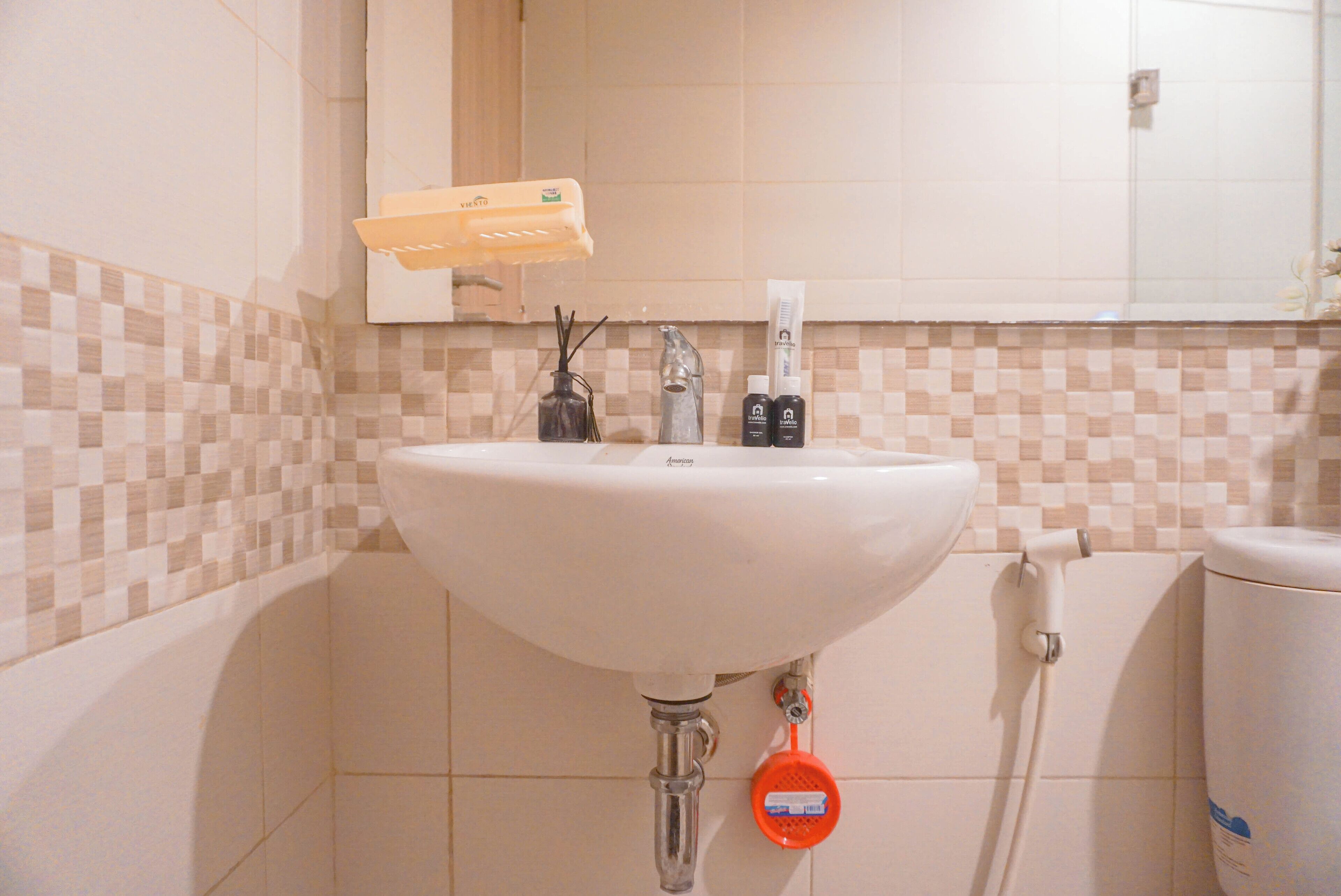 A bathroom with a white sink, a mirror above it, and a tiled wall.