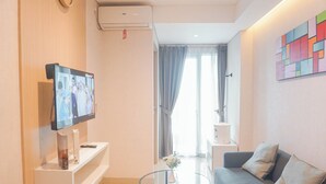 Una sala de estar moderna con una televisión de pantalla plana, una mesa de centro de vidrio, un sofá y una pequeña mesita auxiliar.
