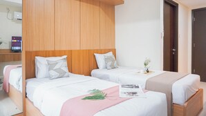 Ein Hotelzimmer mit zwei Betten, Holz-Kopfteilen, weißer Bettwäsche und einem kleinen Nachttisch mit einer Pflanze.