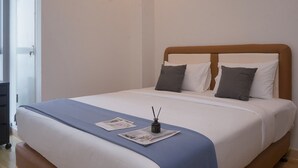 A neatly made bed with a blue bedspread, two pillows, and a small decorative item on the bed.