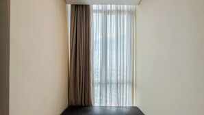 A narrow room with a bench against a wall, a window with sheer curtains, and a view of buildings outside. - Best Price And Relaxing Studio (No Kitchen) At Tamansari Papilio Apartment (Surabaya)