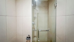 A glass-enclosed shower stall with a handrail, a towel rack, and a control panel. - Best Price And Relaxing Studio (No Kitchen) At Tamansari Papilio Apartment (Surabaya)