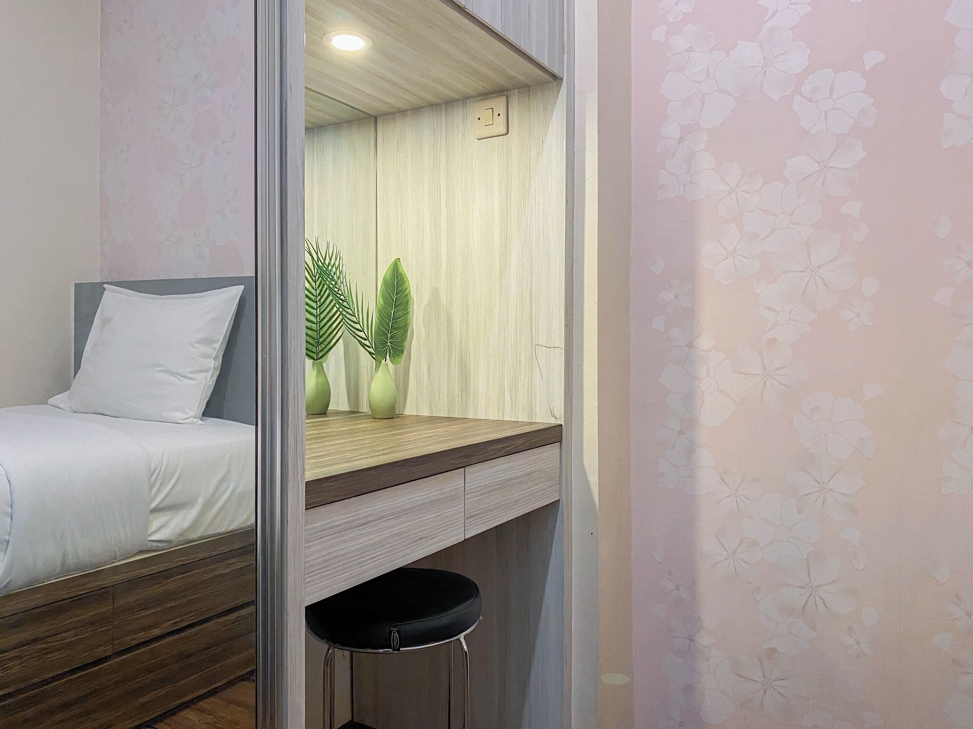 A bedroom with a bed, a nightstand, a mirror, and a small stool.