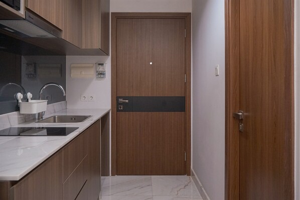 A modern kitchen with a wooden door, built-in cabinets, and a marble countertop.