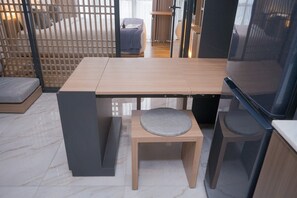 A modern room with a wooden table, two matching chairs, a small stool, and a television. - Warm And Well Designed 1Br At The Smith Alam Sutera Apartment (Tangerang)