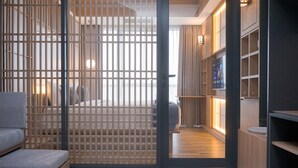 Ein modernes Interieur mit einer schiebbaren Holzwand, einer Couch und einer Holzregaleinrichtung mit Fernseher.