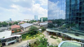 A modern building with a glass facade, surrounded by a landscaped area with pathways and greenery. - Elegant And Best Deal 1Br At L'Avenue Pancoran Apartment (Jakarta)