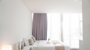 A modern bedroom with a bed, bedside tables, and a window with curtains. - Elegant And Best Deal 1Br At L'Avenue Pancoran Apartment (Jakarta)